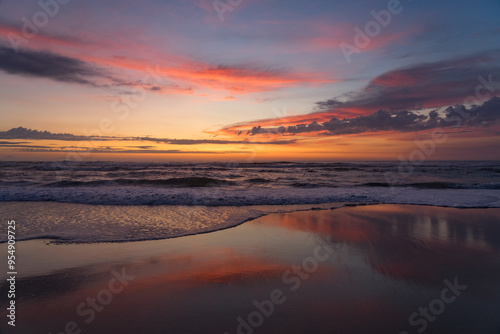 Sunset landscape of a beautiful and paradisaical beach with the clouds reflected on the water. Summer and vacations concept background.