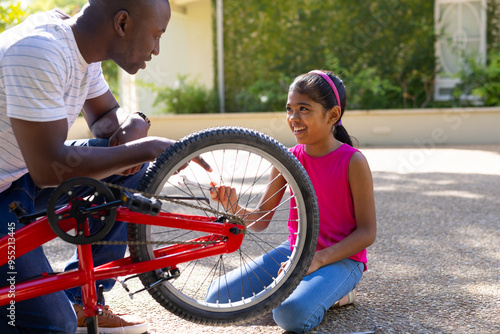 Fixing bicycle, father and daughter bonding outdoors, enjoying quality time together