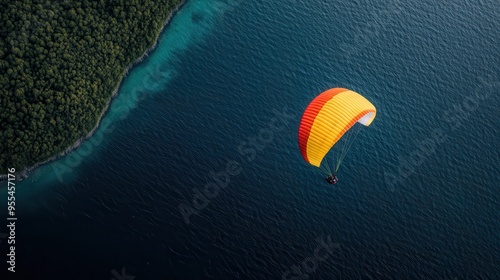 A breathtaking aerial view of a paraglider soaring above a beautiful coastline, with clear turquoise water and dense green forest, capturing an adventurous scene.