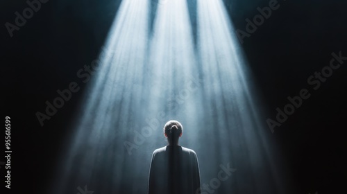 An evocative image showing the back of an individual illuminated by intense beams of white light, creating an ethereal scene that emphasizes feelings of solitude and introspection.