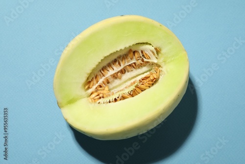 Cut fresh ripe honeydew melon on light blue background, top view