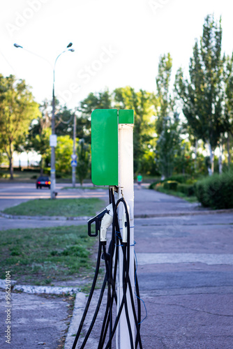 Color vertical photo, electric charging station for electric cars, outdoors on a sunny day, city urban landscape.