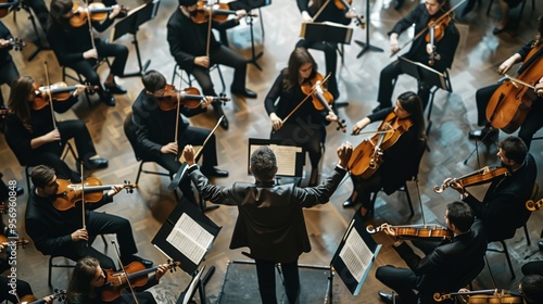 A conductor ardently directs an orchestra from a high-angle perspective, capturing the unity and brilliance of the musicians.