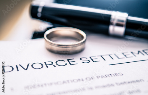 Detailed View of Divorce Settlement Agreement with Wedding Ring and Pen on Document Signifying Legal Separation