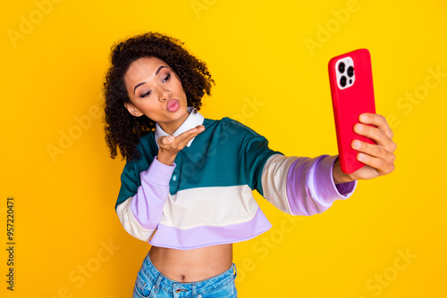 Photo of gorgeous adorable nice woman dressed striped top send air kiss on smartphone make selfie isolated on yellow color background