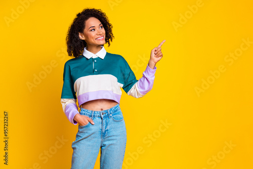 Portrait of optimistic girl with wavy hairstyle wear teal shirt look directing at promo empty space isolated on yellow color background