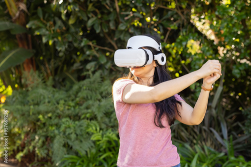 Using VR headset, woman playing virtual reality game outdoors in garden