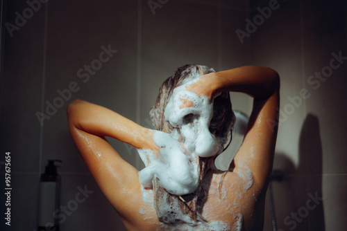 Girl in the Shower Washing her Hair with Cosmetic Shampoo. Woman using a lot of foamy products to clean her hair 