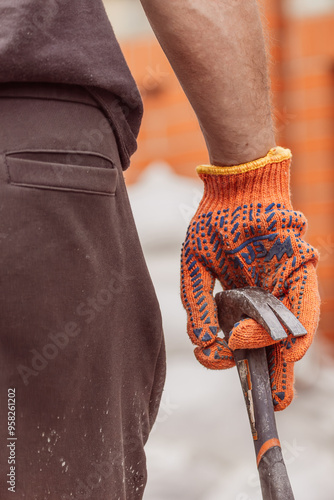 Hammer in male hand. Safety gloves. Place of work. Repair works. Cold weapon. Working calloused hands. Construction process. Work in progress.