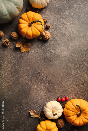 Autumn flat lay with pumpkins, nuts, and fall foliage on a grey textured backdrop. Ideal for fall designs