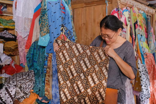 Indonesian woman busy standing and selecting to purchase some used clothes at a thrift store