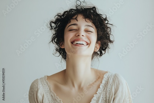 Joyful woman with curly hair laughing heartily