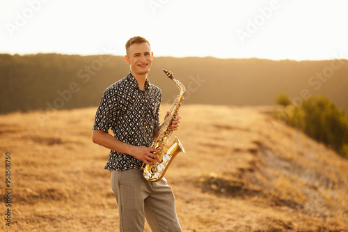 A remarkably talented young saxophonist is enjoying a peaceful and serene sunset on a beautiful landscape backdrop