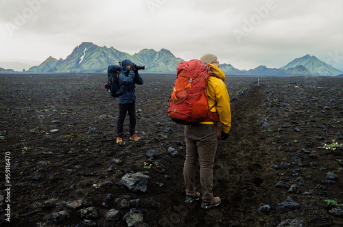 Two hikers on a volcanic lava trail stopping to take photos in Iceland