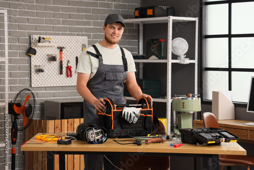 Male worker with bag of tools repairing coffee machine in workshop