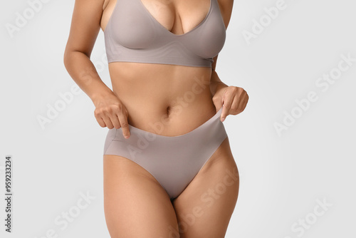 Beautiful young African-American body positive woman on grey background, closeup