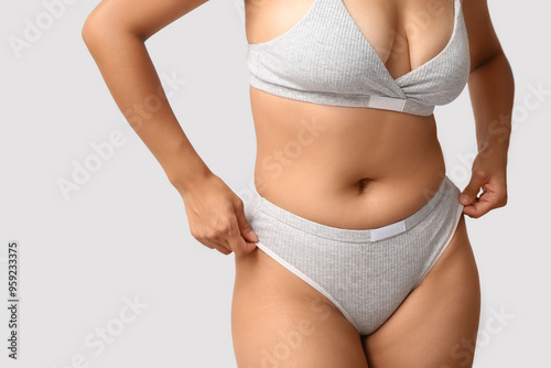 Beautiful young African-American body positive woman on grey background, closeup