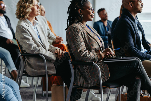 Professionals focused on presentation at business meeting with diverse audience