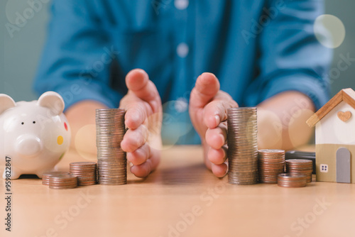 Divorce law and heritage separation concept. Hand separate saving money, financial, home loan, debt with piggy bank and wood house. Bank business investment. Man separate stack coin on table