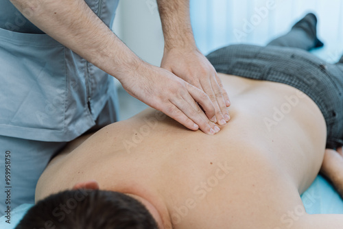 Therapist performing back massage therapy for muscle relaxation and tension relief in clinic