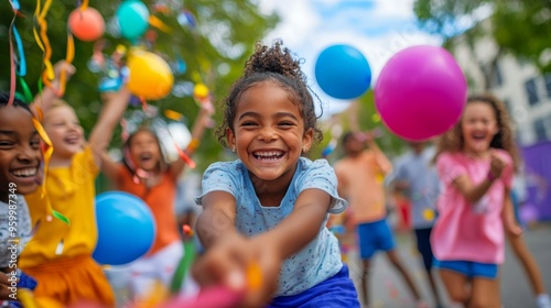 A group of children energetically plays tug-of-war, laughing and cheering amid colorful balloons and festive decorations during a cheerful block party