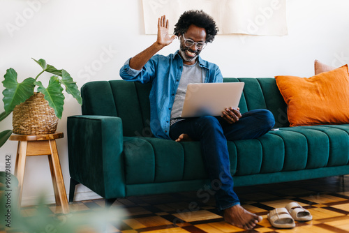 Mature freelancer smiling and waving during a video call from his home office