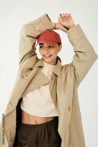 A beautiful young woman showcases her trendy autumn outfit, radiating joy in a sleek studio environment.