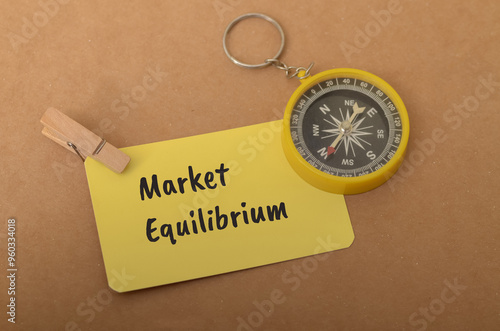 the concept of market equilibrium, with the words "Market Equilibrium" written on a notecard and a compass placed nearby.