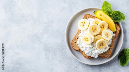 A delicious slice of toast topped with creamy cottage cheese and fresh banana slices, garnished with mint leaves.