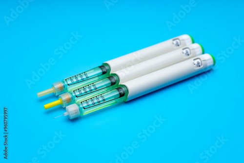 three insulin pens, injector pens on a blue background, top view, for hormone therapy of patients with diabetes. close-up