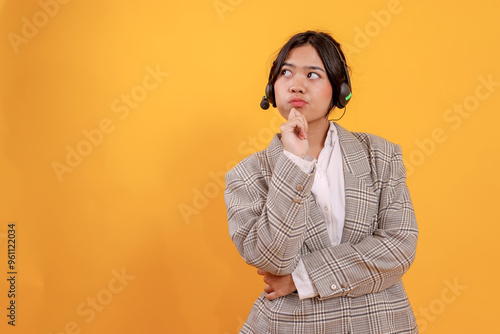 Confused Young Asian Woman Thinking With Looking To Side Isolated on Yellow Background. Customer Service Call center. 