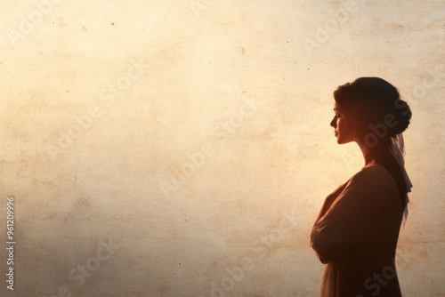 Silhouette of a Modestly Dressed Woman Against Soft, Textured Background in Warm Light