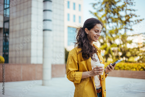 Smiling Woman in Yellow Jacket Using Smartphone Outdoors