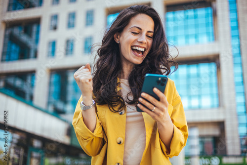 Excited Woman Celebrating Success With Smartphone Outdoors