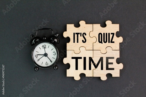 bell clock and wooden puzzle with the word Its Quiz Time. the concept of answering quizzes or quiz games