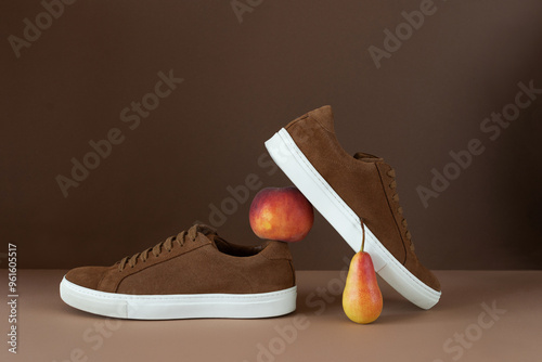 Still life of brown men's minimalist boots with white sole on beige and brown background. Autumn concept