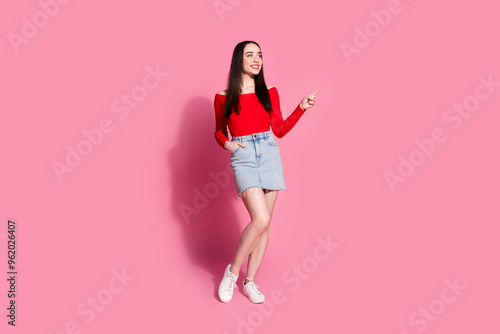 Full body portrait of pretty young girl indicate finger empty space isolated on pink color background