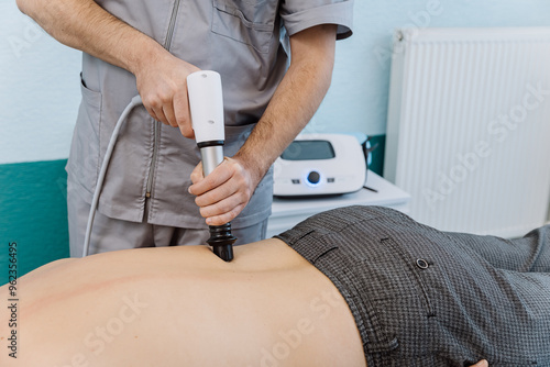 Shockwave therapy session for back pain relief in a clinical setting with a professional therapist