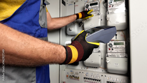 Technician reading consumption and charging on a wireless electricity power meter station in a building.