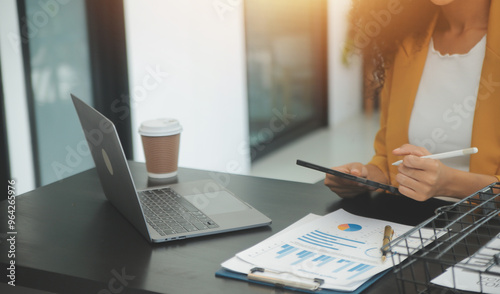 Close up Business woman using calculator and laptop for do math finance on wooden desk, tax, accounting, statistics and analytical research concept