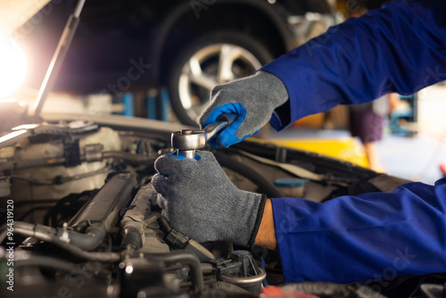 Close up mechanical hand with tools and spanner. Hispanic latin male mechanic repairs car in garage. Car maintenance and auto service garage concept