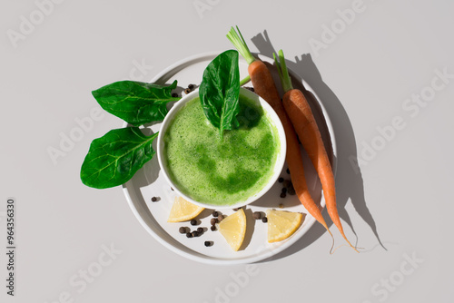 Sopa de espinacas con hojas de espinacas y zanahorias en un recipiente blanco sobre fondo beige. Vista superior 