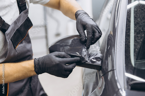 Close-Up of a Professional Applying Protective Film on a Car Mirror in an Auto Workshop