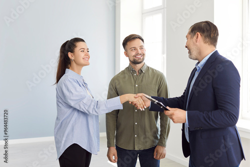 Realtor or agent shakes hands with a couple to confirm the agreement for purchasing or renting a property or apartment. The handshake solidifies the deal, marking a successful real estate transaction.