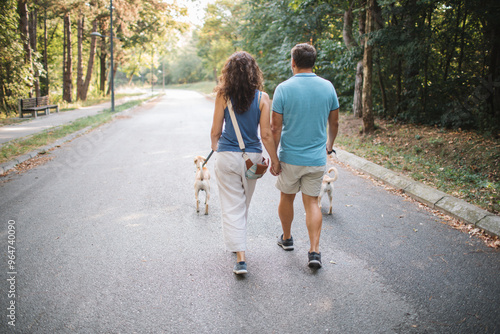 Rear view of couple walking dogs in the park 