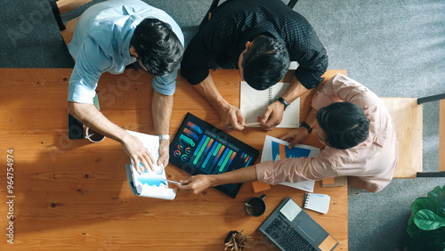 Executive manager explain financial graph to colleague at meeting room. Top aerial view of diverse marketing team sharing idea and planning strategy while sitting at table with tablet. Convocation.