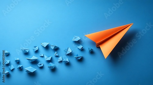 A single orange paper airplane leading a group of blue paper airplanes on a blue background.