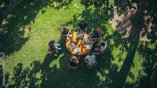 A group of people gathered around a table. Perfect for depicting collaboration or teamwork, this image showcases a team working together in a relaxed outdoor setting.