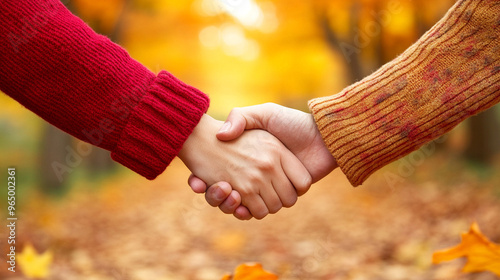 Two people shaking hands in a serene autumn park during the evening, with vibrant fall foliage and a warm sunset. A symbolic gesture of agreement, partnership, and trust in a peaceful setting