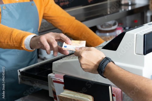 Cash transaction at a register, close-up of a hand exchanging euro banknote. Business